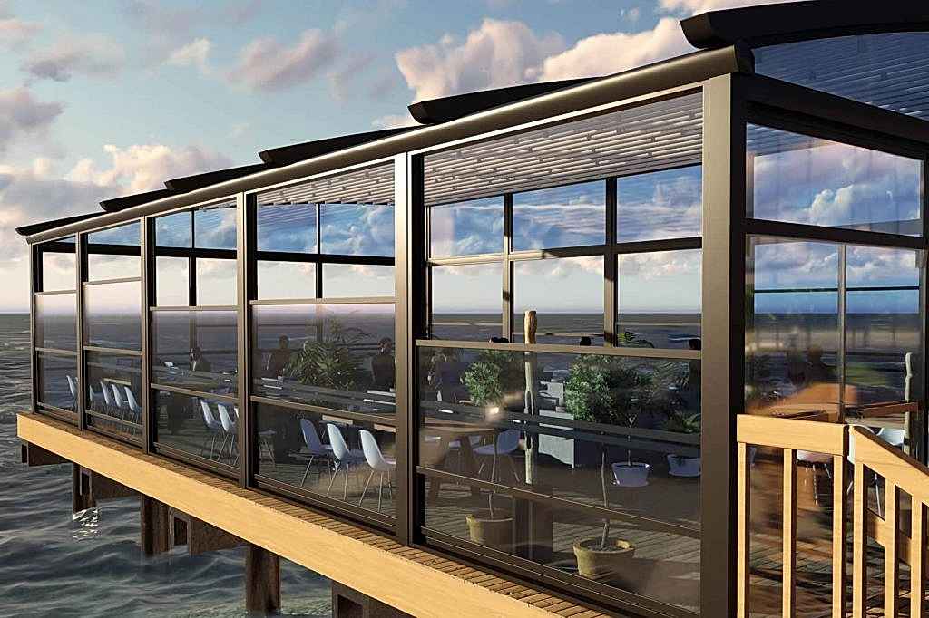 Otomatik giyotin cam sistemleri, dış mekanları dört mevsim kullanılabilir hale getiren motorlu cam sistemleridir. Bu görselde bir kafenin açık alanında uygulanan modern giyotin cam sistemi yer almaktadır.